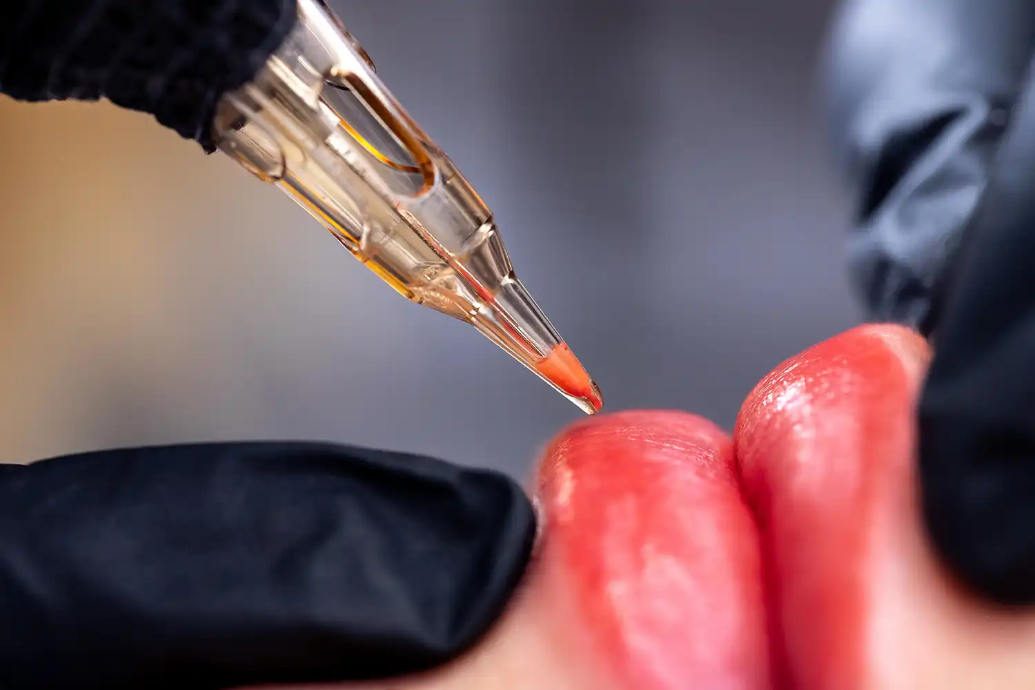 Makro-Foto von Prozess der Anwendung von Permanent-Make-up-Tätowierung von rot auf den Lippen Frau